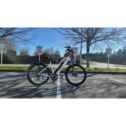 White electric bike on a paved road with trees and signs in the background