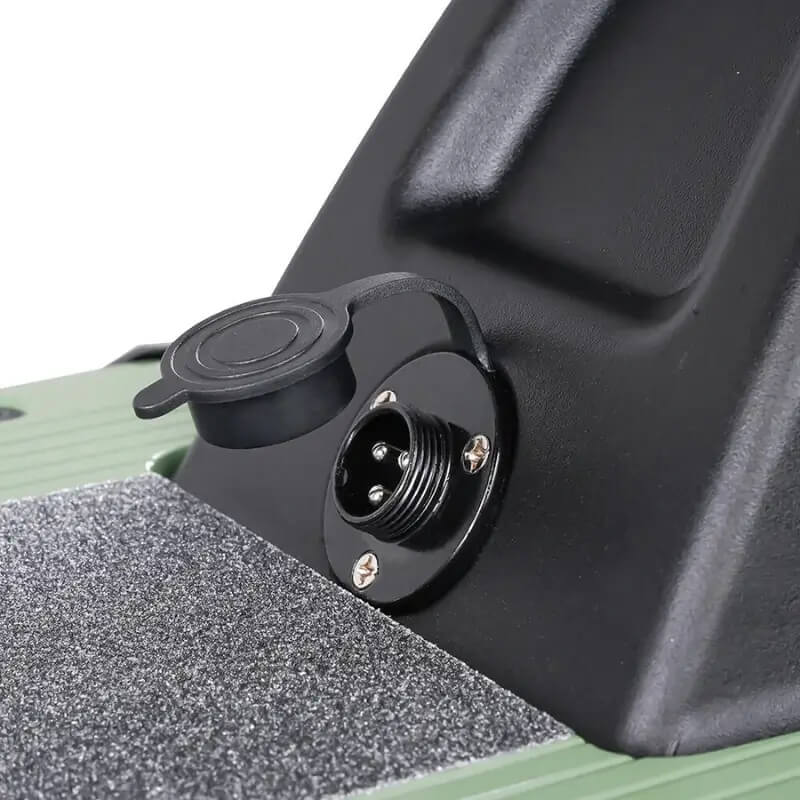 Close-up of a black electrical connector on a green and black vehicle component.