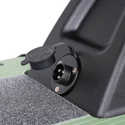 Close-up of a black electrical connector on a green and black vehicle component.